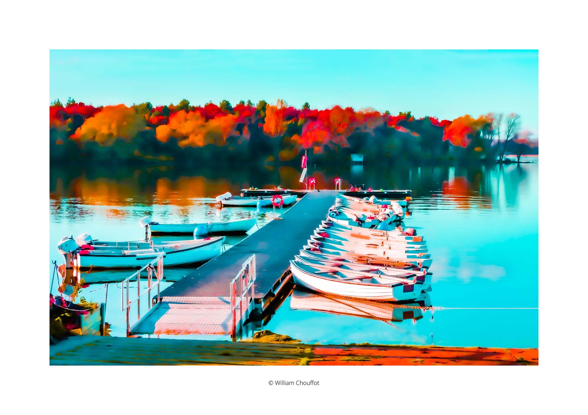 An open edition photography print by William Chouffot, featuring boats by a jetty at Hanningfield Reservoir. The scene shows still waters mirroring vivid autumn foliage in rich reds, oranges, and golds, alongside the orderly rhythm of moored boats. A soft painterly treatment enhances the tranquillity of the lake setting. This open edition version is distinguished by the artist’s © mark in the white border beneath the image, making it an accessible contemporary wall art option for collectors and enthusiasts 
